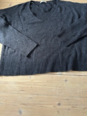 Mörkblå stickad tröja med v-ringning - Mysig mörkblå stickad tröja med v-ringad hals och långa ärmar. Tröjan har ribbstickade muddar vid ärmslut och nederkant. Perfekt för lager på lager och enkel att matcha till olika outfits.