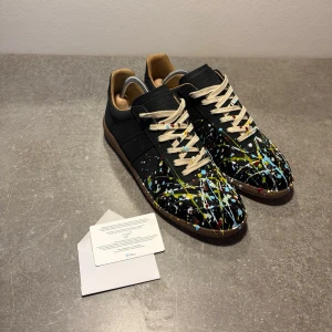 Maison margiela gats - Tja! Säljer dessa Maison Margiela Paint Splatter GATs.  Storlek 44, sparsamt använda och i fint skick. Svart bas med färgstänk. Fungerande NFC.  Endast box och dustbag ingår.  Pris kan diskuteras vid snabb affär. Hör av dig vid frågor!