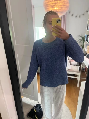Blå stickad tröja med rund hals - Mysig blå stickad tröja med rund halsringning och långa ärmar. Tröjan har en enkel, rak passform och är perfekt för att hålla värmen under kyliga dagar. Materialet ser ut att vara mjukt och bekvämt, perfekt för en avslappnad stil.