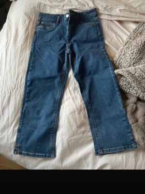 Blå raka jeans Jane Capri M - Säljer ett par klassiska blå jeans i rak modell från Jane Capri. Jeansen har hög midja, fem fickor och kontrastsömmar. Perfekta till vardagslooken och passar till det mesta. Materialet är tålig denim i bomull.