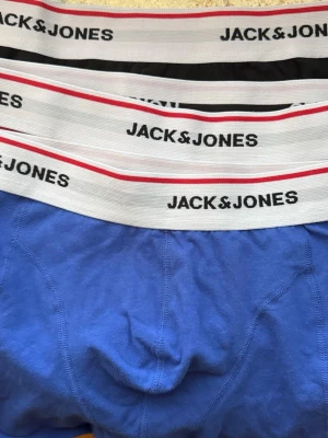 3 pack  kalsonger från Jack & Jones - 3 pack kalsonge,  blåa, röd och svarta kalsonger från Jack & Jones med bred resår i vitt, svart och rött med logga runtom. Kalsongerna är i mjukt och stretchigt material, perfekta för en bekväm vardag. Klassisk passform och snygg design.