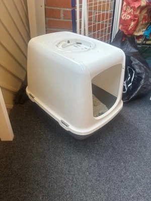 Vit kattlåda med lock - En vit kattlåda i plast med lock och öppning framtill. Lådan har rundade hörn och ett handtag på toppen för enkel hantering. Perfekt för att hålla sanden på plats och ge katten lite extra avskildhet. Säljer pga jag har två hemma, pris från början 499kr