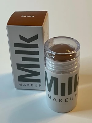 Milk Makeup Cream Bronzer Stick Baked - Milk Makeup Cream Bronzer Stick i nyansen Baked är en krämig bronzer i stickformat. Färgen är medium bronze med varm underton och ger ett naturligt solkysst resultat. Förpackningen är vit med grå text och genomskinligt lock, enkel att applicera och perfekt för contouring.