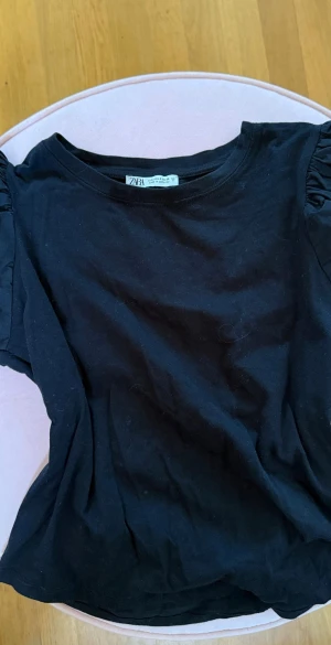 Svart t-shirt från Zara - En svart t-shirt från Zara med puffiga korta ärmar och rund halsringning. 
