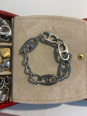 Silverfärgat chunky länkarmband - Säljer ett stilrent armband i silverfärgad metall med chunky, ovala länkar. Länkarna har en unik design med utskurna detaljer som ger ett modernt och edgy uttryck. Perfekt accessoar för att lyfta din outfit.