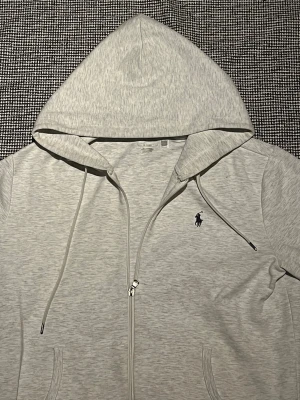 Ljusgrå hoodie med dragkedja - Snygg ljusgrå hoodie från Polo Ralph Lauren priset går att diskutera  