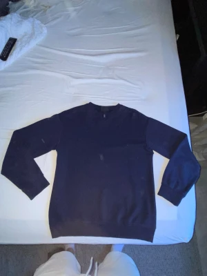 Mörkblå basic sweatshirt - En enkel och stilren mörkblå sweatshirt med rund hals och långa ärmar. Tröjan har ribbade muddar vid ärmslut och nederkant. Perfekt att matcha med jeans eller joggers för en avslappnad look.