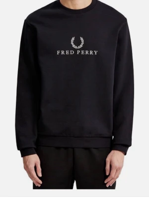 Svart sweatshirt från Fred Perry - Svart sweatshirt från Fred Perry med klassisk rund halsringning och vit logotyp samt lagerkrans broderad på bröstet. Tröjan har ribbade muddar vid ärmslut och nederkant. Perfekt för en clean och stilren look. Använt den minst 3 gånger så är helt ny typ. Pris kan diskuteras 