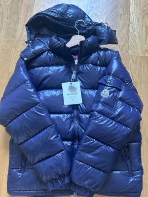 Moncler Maya - Säljer denna snygga Moncler Maya i marinblå färg med storlek M. Aldrig använd skick 10/10. Perfekt inför hösten och vintern nu. Mitt pris 2299kr kan gå ner lite vid snabb affär. Vid intresse eller frågor hör av er!
