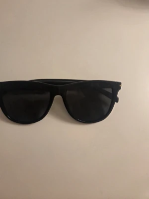 Svarta klassiska solglasögon - Snygga svarta solglasögon med klassisk rak båge och mörka glas. Passar perfekt till alla outfits och ger en cool vibe. Ramen är i plast och modellen är tidlös och enkel att matcha.
