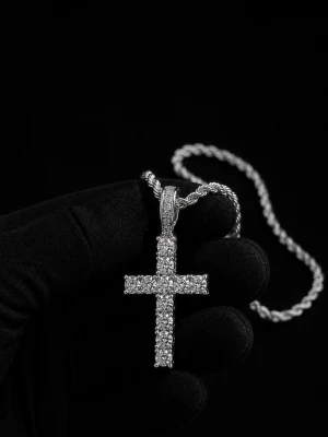 Cordell Halsband - Snyggt halsband i silverfärg med ett korsformat hänge täckt av gnistrande stenar. Kedjan har en tvinnad design som ger extra stilpoäng. Perfekt för dig som gillar statement-smycken och vill sticka ut lite extra.