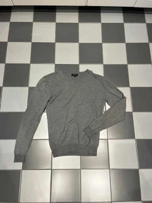 Mantinique - En stilren grå sweatshirt med rund halsringning och långa ärmar. Tröjan har ribbade muddar vid ärmslut och nederkant, vilket ger en snygg passform. 