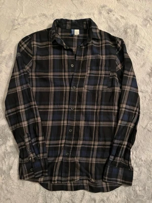 Rutig blå och grå skjorta Divided - Säljer en rutig skjorta från Divided i blått och grått. Skjortan har långa ärmar, klassisk krage och knäppning framtill. Perfekt för en avslappnad och stilren look. Tillverkad i mjuk bomull för skön känsla hela dagen.