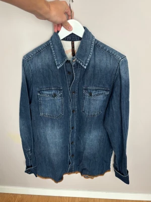 Superfin Nudie jeanskjorta S - Jättefin blå populär stentvättad Nudie jeanskjorta i storlek S av högsta kvalité. Grym skjorta i utmärkt toppskick och väldigt unik! Tveka inte vid minsta fråga eller fundering!