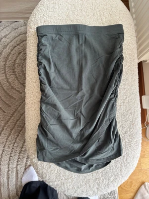Grön kjol från Lindex - Säljer en grön kortkjol från Lindex i mjukt bomullsmaterial. Kjolen har en enkel, rak passform med rynkade sidor som ger en snygg detalj. Perfekt att matcha med en crop top eller oversized tröja.