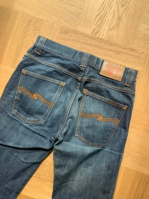 Nudie Jeans Slim Jim - Riktigt snygga dry denim Nudie Jeans i modellen Slim Jim. Jeansen har tecken på användning vilket höjer jeansen visuellt. Storlek 28 - utgå från angivna mått.   Mått Midja: 39	 Ytterben: 94 Innerben: 71 Benöppning: 19  Skriv vid frågor eller funderingar!