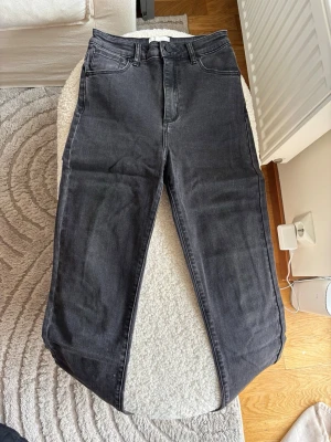 Svarta jeans från Abrand - Säljer ett par svarta jeans med rak passform och hög midja. Jeansen har klassisk femficksdesign och stängs med dragkedja och knapp. Materialet är denim i bomull med lite stretch för extra komfort.