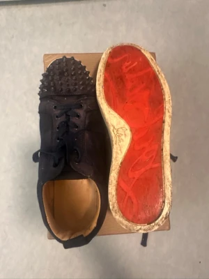 Christian loubutin - Marinblå sneakers från Christian Louboutin med coola nitar på tån och den ikoniska röda sulan. Skorna har snörning och är tillverkade i tyg och läder. Perfekta för dig som vill sticka ut med din stil. Jag har bevis att de är äkta priset går också att diskutera. Jag säljer de för ganska billigt för det är inte i så bra skick. Mer info skriv