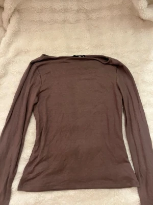 Brun långärmad topp från 157 - Säljer en enkel och stilren brun långärmad topp från 157 i storlek XS. Toppen har en tight passform och är tillverkad i ett mjukt bomullsmaterial. Perfekt att matcha med jeans eller kjol för en clean look.