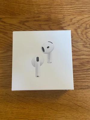 Trådlösa vita hörlurar - Säljer ett par trådlösa vita hörlurar med stilren design och laddningsetui. Hörlurarna har en slimmad form och sitter bekvämt i öronen. Perfekta för musik, poddar och samtal. Laddningsetuiet är kompakt och enkelt att ta med sig.