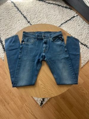 Blå Replay hyperflex - Hej👋 Säljer dessa blå replay med snygga slitningar och klassisk femficksmodell i storlek W29 L30 och Jondrill modell🤩 Jeansen har ljusare partier framtill och bakfickor med dekorativa sömmer🧵 Tillverkade i mjukt och skönt denimtyg med normal midja och bälteshällor, även hyperflex material vilket ger en skön stretchande känsla😮‍💨 Meddela gärna vid fler frågor!📩