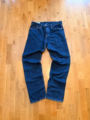 H&M relaxed fit jeans - Klassiska mörkblå jeans med rak passform och fem fickor. Jeansen har normal midja, knappgylf och kontrastsömmar. Tillverkade i kraftigt denimtyg som ger en tidlös look. Perfekta för dig som gillar enkel och stilren stil.