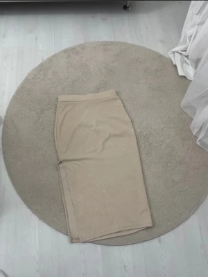 Beige ribbad långkjol - Snygg beige långkjol med ribbad struktur och rak passform. Kjolen har en enkel och stilren design som passar perfekt till många olika outfits. Mjuk och bekväm att bära.