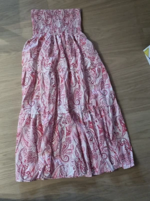 Rosa och vit långkjol med paisleymönster - Säljer en flowy långkjol i rosa och vitt med snyggt paisleymönster. Kjolen har smock i midjan.      #baggyjeans #lowwaist jeans #cargobyxor #vida jeans #flarejeans #lågmidja #rakajeans #kostymbyxor #mjukisbyxor #oversizedhoodie #ziphoodie #stickadtröja #corsettopp #offshoulder #babytee #linne med spets #oversized tshirt #stickadväst #maxikjol #y2k #vintage #streetwear #oldmoney #cleangirl #basic #festkläder #vardagskläder #unisex #oversized #fitted #cozy #retro #zara #hm #bikbok #ginatricot #nel