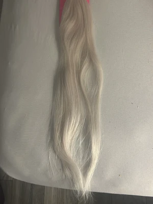 Långt blont löshårsvax - Säljer ett paket med 20 oanvända  tejp löshår, som är 55 cm långt, vågigt löshår i en kall blond nyans. Håret är tejp fästen, och hålls ihop med ett gummiband. Perfekt för dig som vill fixa en ny frisyr eller förlänga ditt hår snabbt.