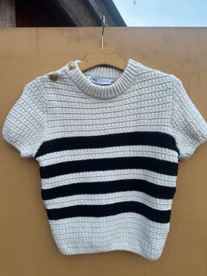 Stickad kortärmad från Zara  - En tjock stickad kortärmad tröja i storlek S från Zara med guldiga knappar på axeln. endast använd 2 gånger💘 köparen står för frakten 