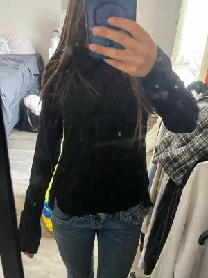 Svart långärmad polotopp - En svart långärmad polotopp med slim passform. Toppen har en klassisk polokrage och är enkel att matcha med olika outfits. Perfekt för dig som gillar en stilren och tidlös look.