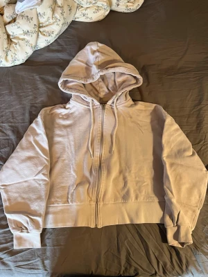 Ljuslila hoodie med dragkedja från 157 - Säljer en ljuslila hoodie från 157 i storlek M. Hoodien har dragkedja framtill, justerbar huva med snören och ribbade muddar vid ärmar och nederkant. Insidan är mjuk och fleecefodrad, perfekt för chill dagar.