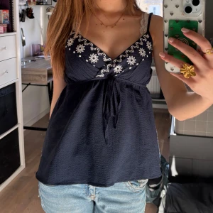 Mörkblå linne med broderade blommor - Jättegulligt blus-linne i marinblå💕 Storlek xs och banden går att spänna💕