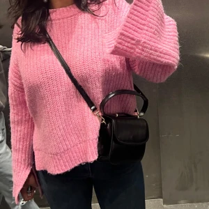 Rosa stickad tröja - Säljer en mysig rosa stickad tröja med långa ärmar. Perfekt för kyligare dagar och ger en härlig färgklick till garderoben. Tröjan har en avslappnad passform och ribbade detaljer vid ärmslut och nederkant.