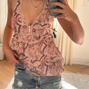 Mönstrad rosa halterneck-topp - Supersnygg rosa halterneck-topp med coolt mönster i rött och beige!! Toppen har en djup v-ringning och knytning i ryggen 😍 Perfekt till sommaren!☀️☀️(säljer även shortsen i bilderna)