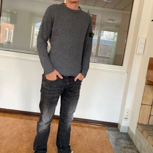 Grå tröja från Stone Island Junior - Snygg grå tröja från Stone Island. Den har en klassisk design med ribbade muddar och en diskret logga på ärmen. Perfekt för en stilren look. Sitter som xs eventuellt en lite mindre s. Den har ett litet hål nere vid midjan, går att laga. Modellen på bilden är 175. Förutom hålet är det bra skick. Hör av dig vid frågor!