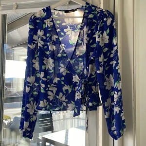 Blå knut blus med vita blommor - Fin tun blus med vita blommor, blusen knyts framtill med en rosett. Den är mörkblå och väldigt bra för varma dagar.🙌💕