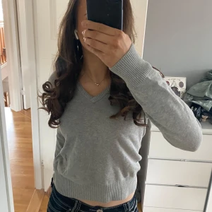 Grå v-ringad tröja - Säljer en stilren grå v-ringad tröja med långa ärmar. Perfekt för en avslappnad look. Tröjan har ribbade muddar vid ärmslut och nederkant. Storlek M men passar mig som oftast bär xs/s, bilderna är mina egna. Andvänd ca 1 gång. Pris kan diskuteras 