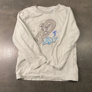 Grå långärmad tröja med skateboardtryck från NKY storlek 110 - Säljer en grå långärmad tröja från NKY med ett coolt skateboardtryck. Tröjan är tillverkad i 100% bomull, vilket gör den mjuk och bekväm att bära. Perfekt för den lilla skateboardentusiasten! 🛹  Bomull Längd: 42 cm Från armhåla till armhåla: 44 cm Katter finns i hemmet 