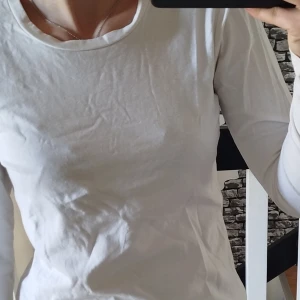 Vit långärmad tröja - Säljer en klassisk vit långärmad tröja i bomull. Perfekt för lager-på-lager eller som den är. Enkel och stilren design med rund halsringning.