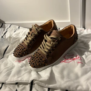 Christian Louboutin skor  - Snygga bruna sneakers från Christian Louboutin med nitar på tå och häl. Skorna är i super skick! Dustbag extra nitar, kort kommer med. Priset är ej hugget i sten. Om ni har fler frågar kom privat! 😉Jag är även öppen för byte för ett par andra skor i storlek 45🙌