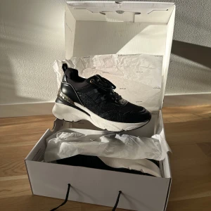 Sneakers - ALDO - Thaliri - Svarta sneakers med guldfärgade detaljer. Nya, aldrig använda, kommer i orginalförpackning. (Två sista bilderna är lånade från Asos där skorna är köpta från).