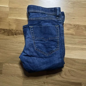 Diesel Tepphar jeans blå W30 L30 - Säljer ett par blå Diesel Tepphar jeans i stretchigt material. Modellen har smal passform med klassiska fem fickor och snygga kontrastsömmar. Perfekta för dig som gillar en modern och stilren look. Midjan är normal och benen är raka.