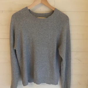 Grå stickad tröja från Vero Moda - Mysig grå stickad tröja från Vero Moda i storlek XS. Tröjan har rund halsringning, ribbade muddar och är långärmad. Perfekt för lager-på-lager och enkel att matcha med jeans eller kjol.