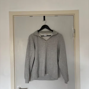 Grå half zip hoodie från Zara - Säljer en stilren grå hoodie från Zara med half zip-dragkedja. Tröjan har lång ärm, mjukt material och en klassisk huva. Perfekt för dig som gillar en enkel och clean look. Passar till jeans eller mjukisbyxor.