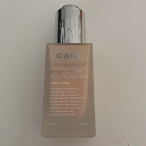 CAIA Dewy Drops Serum Foundation 10C - CAIA Dewy Drops Serum Foundation i nyansen 10C. Kommer i en frostad glasflaska med silvrig pump. Ger en naturlig, daggig finish och innehåller vitamin E och glycerin för återfuktning. Perfekt för dig som vill ha en lätt och fräsch bas.