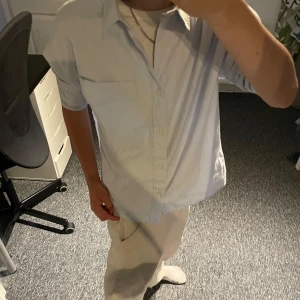 Ljusblå skjorta från Zara, strl 164 - Snygg ljusblå skjorta från Zara i storlek 164. Skjortan har klassisk krage, bröstficka och knäppning framtill. Tillverkad i mjuk bomull, perfekt för en clean och stilren look. Passar dig som gillar enkel och fräsch stil.