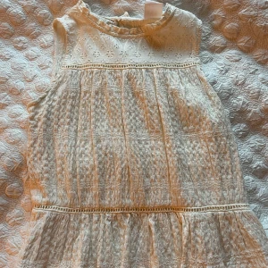 Vit ärmlös klänning från Zara - Supergullig vit mönstrat linne från Zara med broderade blommor upptill. Ärmlös modell med liten volang vid halsen och fina spetsdetaljer. Perfekt för sommarens alla tillfällen!