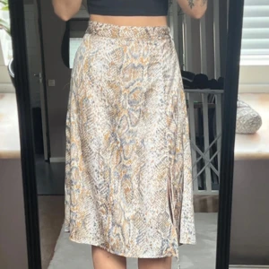 Mönstrad kjol från Vero Moda - Fin kjol i superbekväm tyg som andas under varma sommardagar. Kjolen har en justerbar snöre på högerbenet så man kan själv styla den som man vill. 