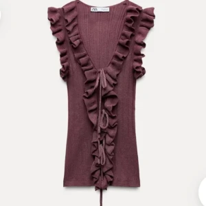 Lila volangtopp med knyt från Zara - Supersöt lila topp från Zara med volanger längs v-ringningen och framtill. Toppen är ärmlös och har snygg knytning framtill som ger en extra detalj. Perfekt för dig som gillar romantiska vibes och vill sticka ut lite extra. Är i storlek M men sitter bra på mig som brukar ha xs-s och känns M för litet? Inga problem den är jätte stretchig !